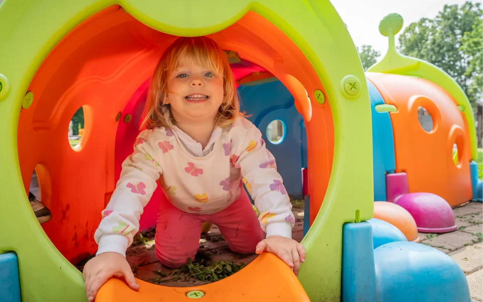 Una bambina gioca in uno spazio educativo all’aperto