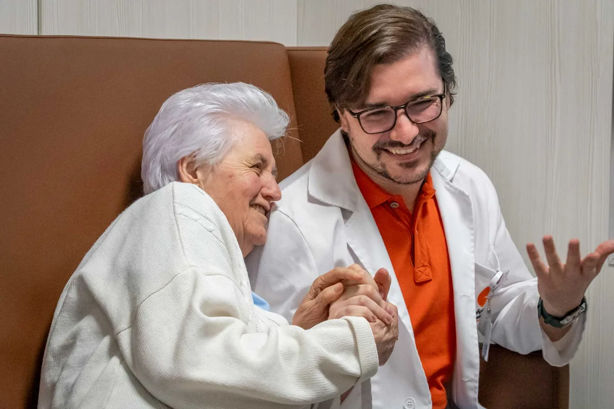 Una persona anziana sorride insieme a un professionista di Nuova Assistenza